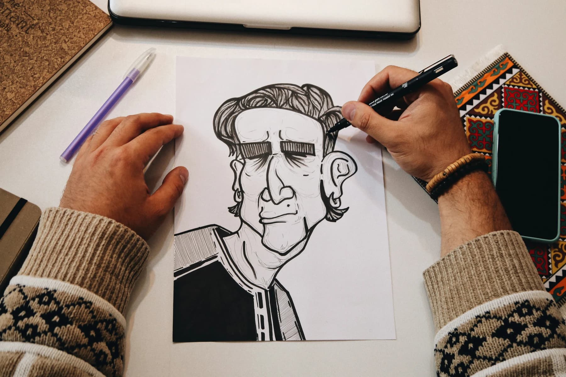 Photograph of hands drawing a portrait on paper.